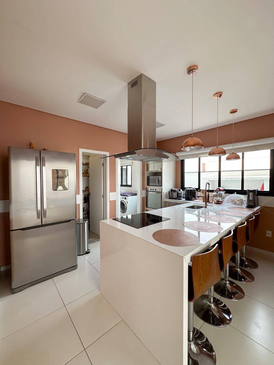 Cozinha moderna com ilha central, cooktop e eletrodomésticos em aço inox